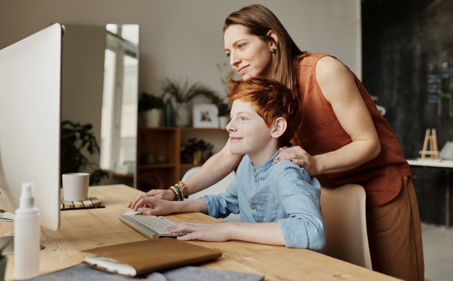 mother stands behind child on computer Orlando Catholic School