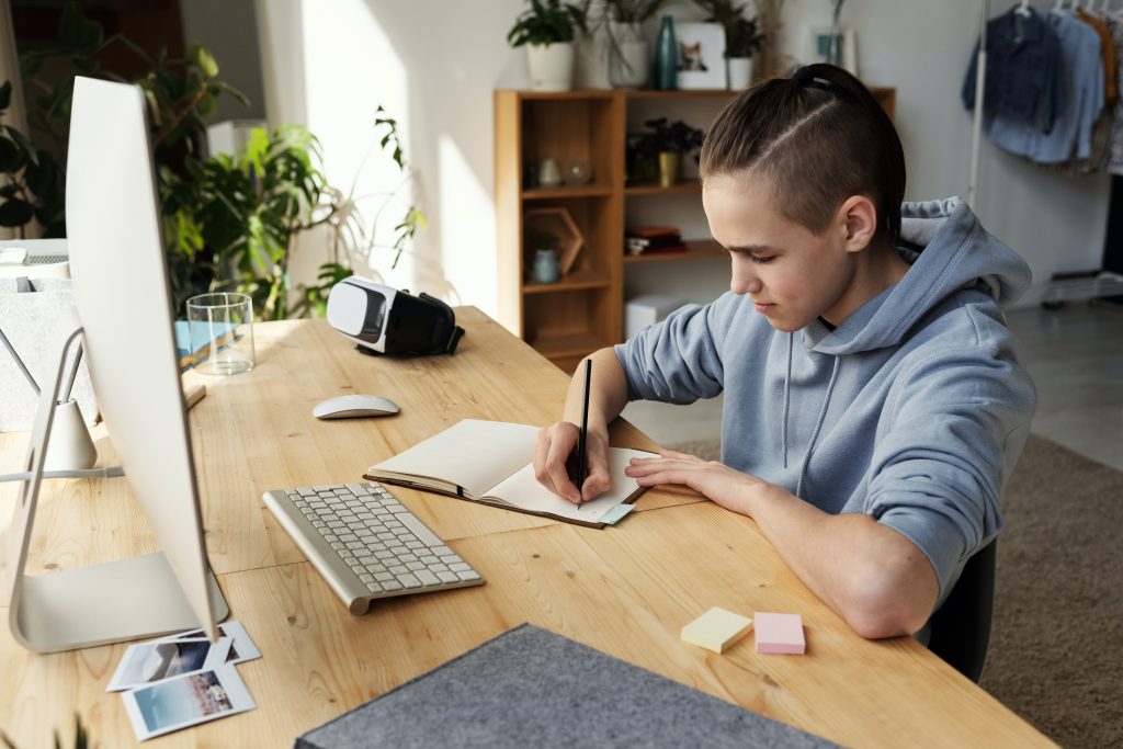 boy studying at desk with notebook and computer