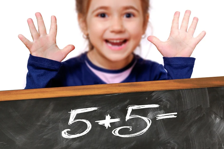 child holding up fingers above chalkboard