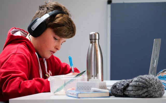 child doing homework with headphones