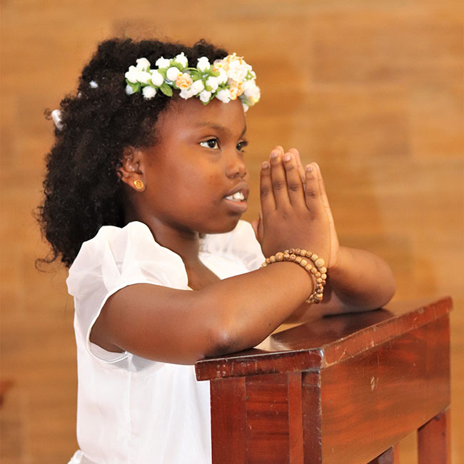 child praying in First Communion dress